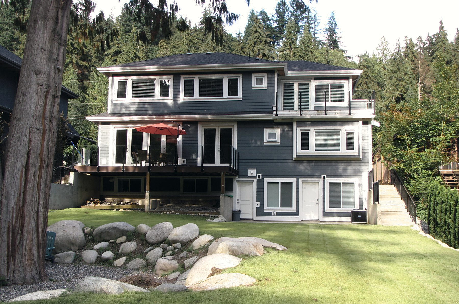 The house at Riverfront Bed and Breakfast, seen from the back garden with its river rocks and tall evergreens behind